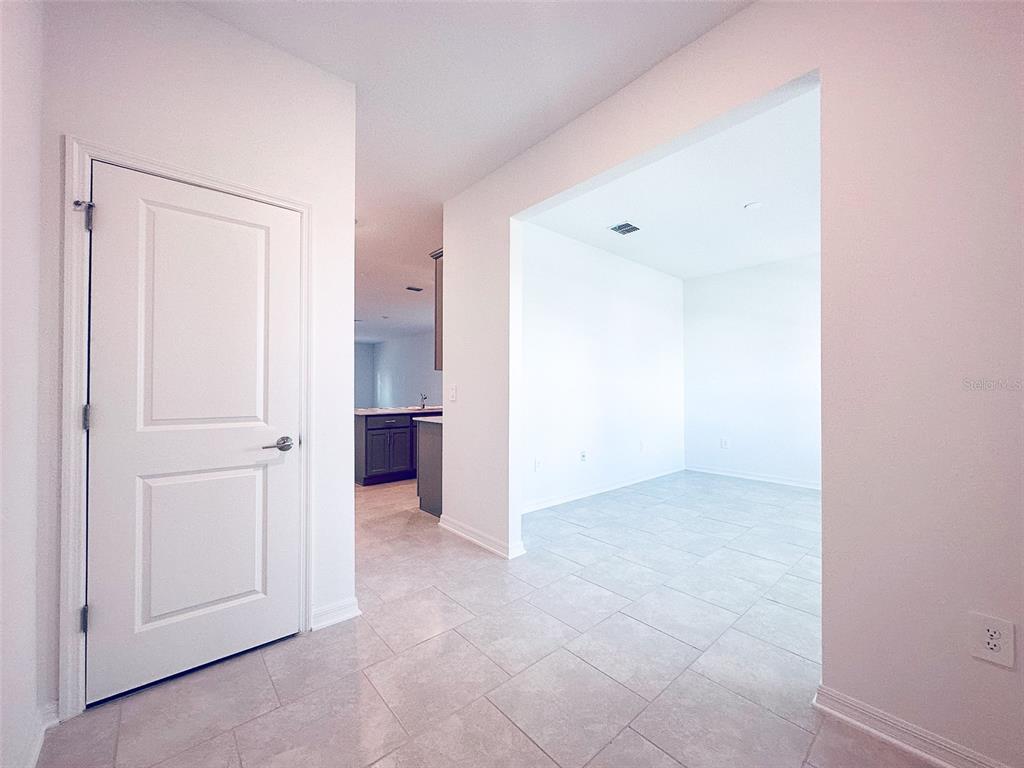 A white door opens to a tiled room with a view into a kitchen area — 4155 CONJUNCTION WAY, APOPKA, FL