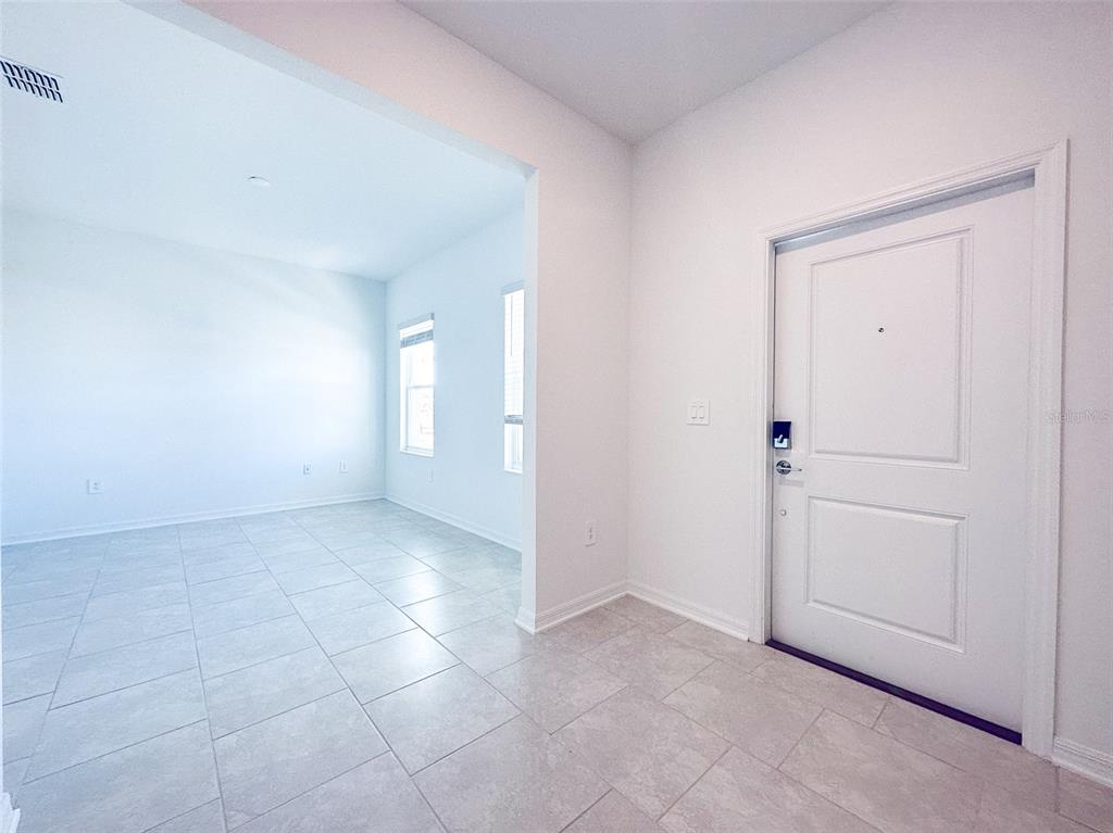 An entryway with light tile flooring leads into an adjacent room with two windows — 4155 CONJUNCTION WAY, APOPKA, FL