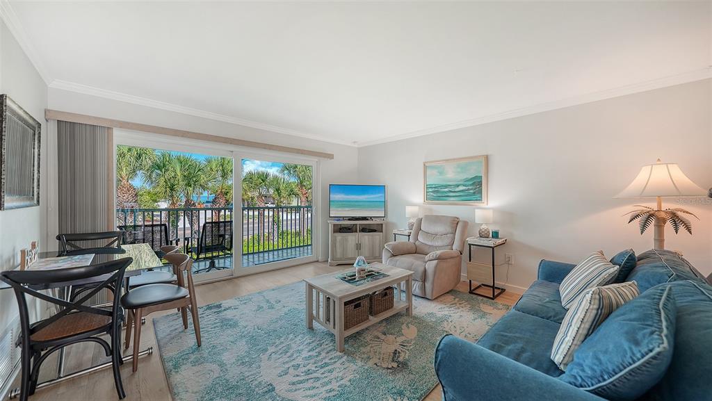 A living room features a blue sofa, a patterned rug, and a sliding glass door — 2850 GULF OF MEXICO DRIVE UNIT 4, LONGBOAT KEY, FL
