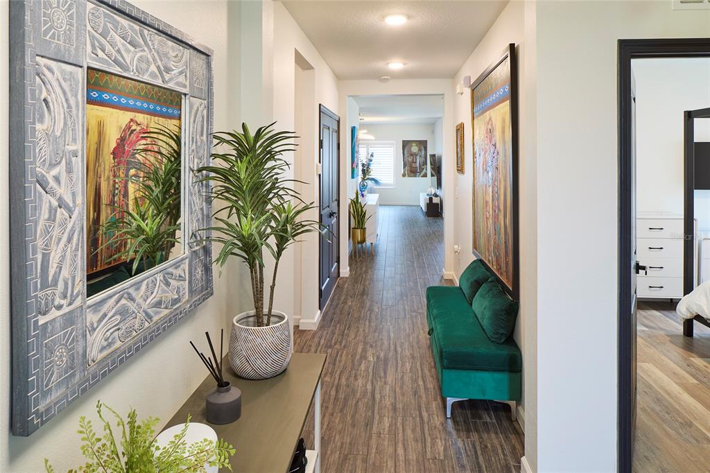 A hallway features wood-look tile flooring, a green velvet bench, and decorative wall art — 832 CAMBRIDGE DRIVE, WINTER HAVEN, FL