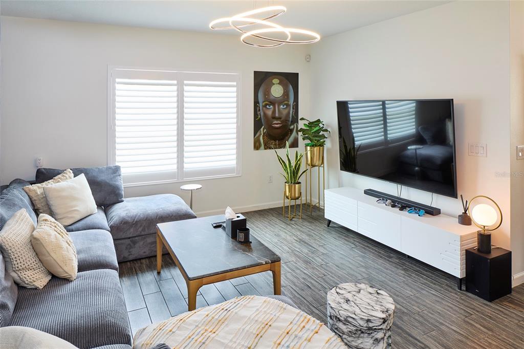 A modern living room features a grey sectional sofa, marble coffee table, and wall-mounted television — 832 CAMBRIDGE DRIVE, WINTER HAVEN, FL