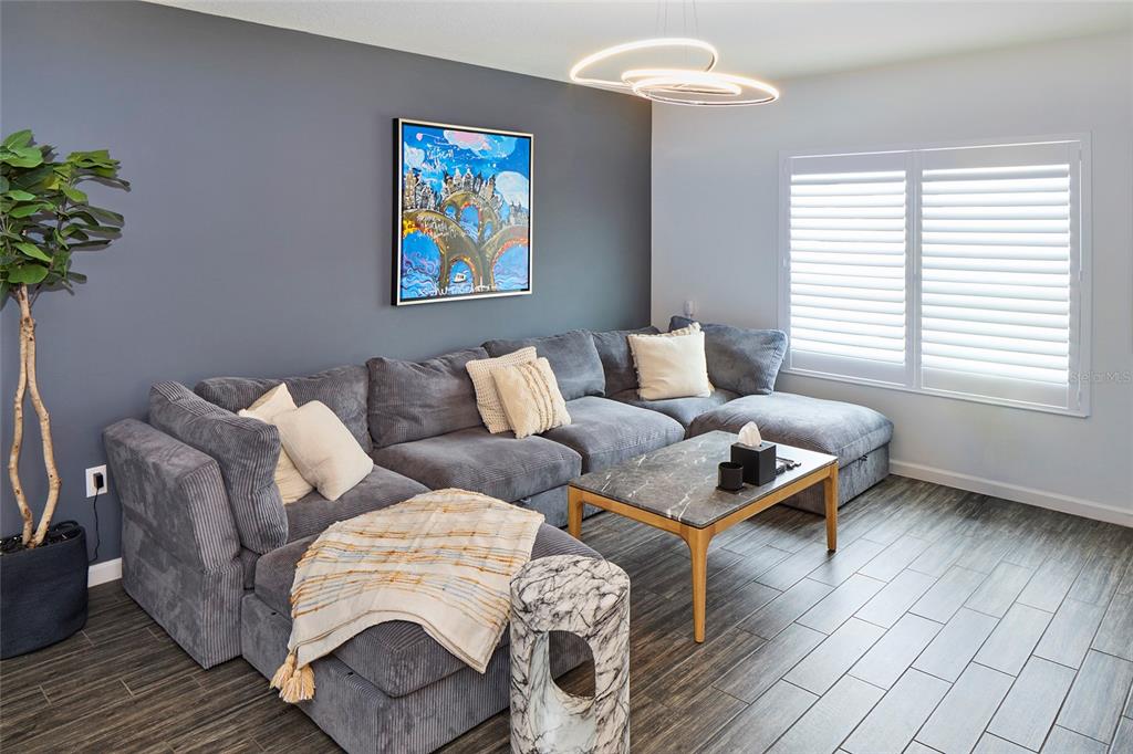 A living room features a grey sectional sofa, a marble coffee table, and dark flooring — 832 CAMBRIDGE DRIVE, WINTER HAVEN, FL