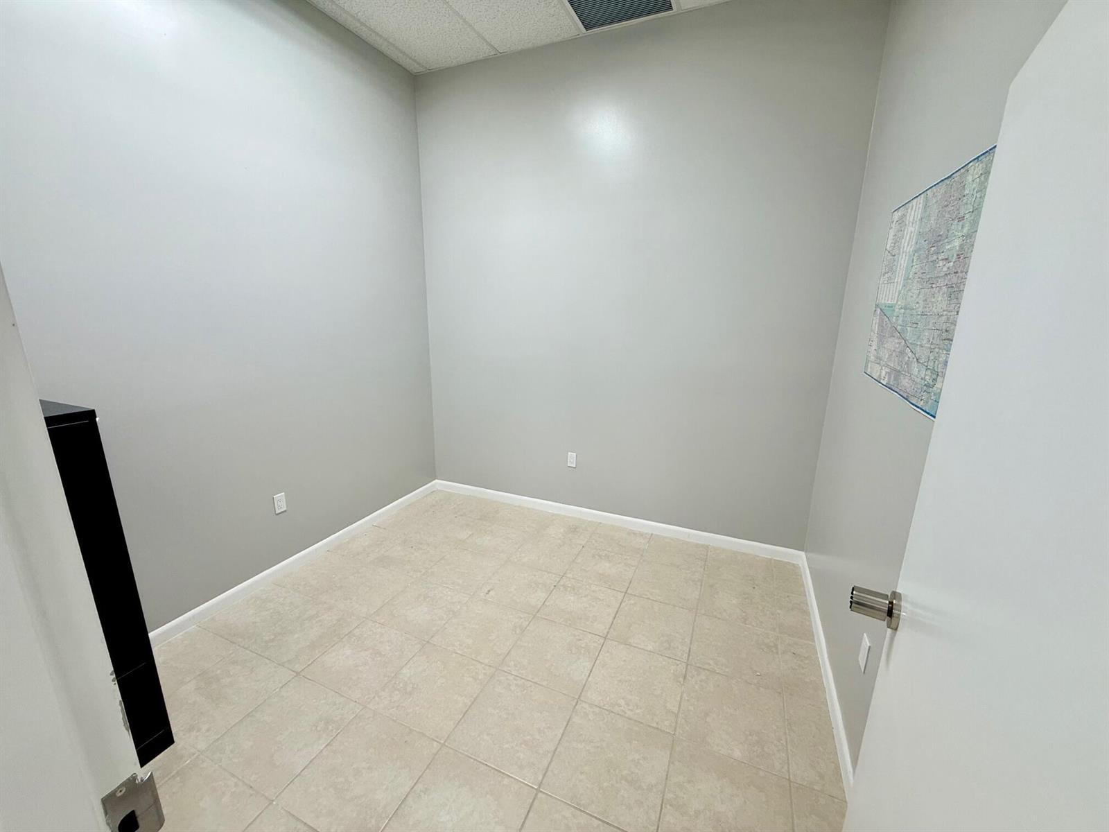 An empty office with gray walls, beige tile flooring, and a map on the wall — 1490 N State Road 7 # B, Margate FL 33063, MARGATE, FL