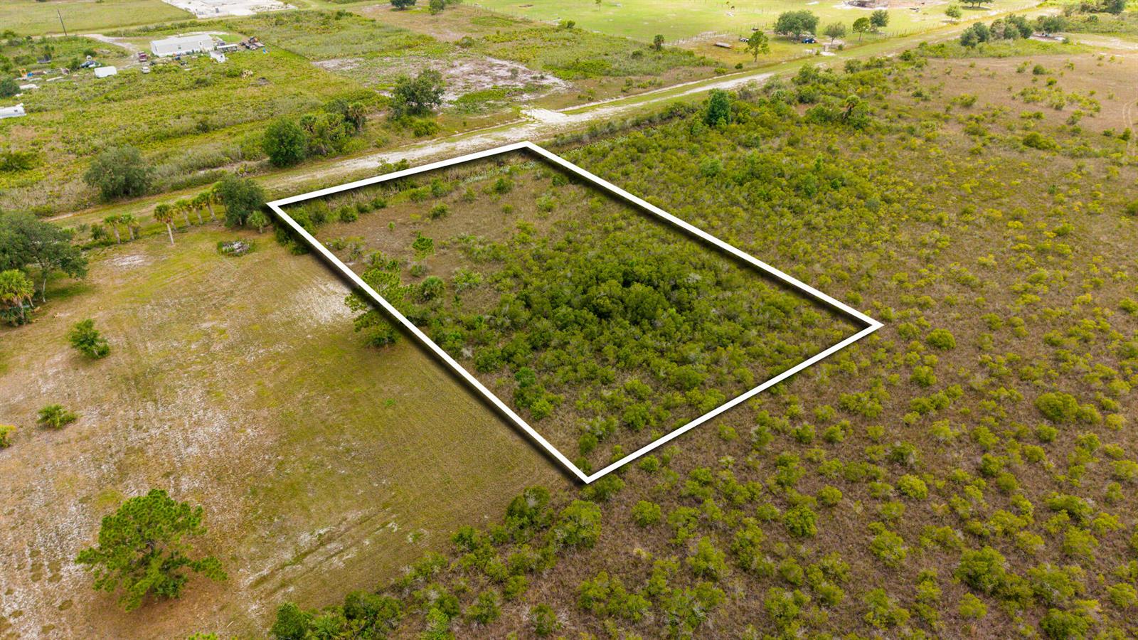 An aerial view shows a rectangular plot of land outlined in white amidst grassy terrain — 16841 NW 300th Street, Okeechobee FL 34972, OKEECHOBEE, FL