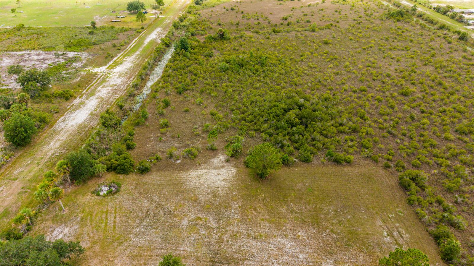 An aerial view shows a cleared rectangular patch of land adjacent to a dirt road — 16841 NW 300th Street, Okeechobee FL 34972, OKEECHOBEE, FL