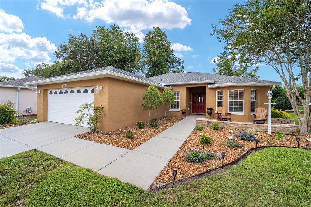 A single-story tan stucco house with a two-car garage and a landscaped front yard — 7962 SW 83RD PLACE, OCALA, FL