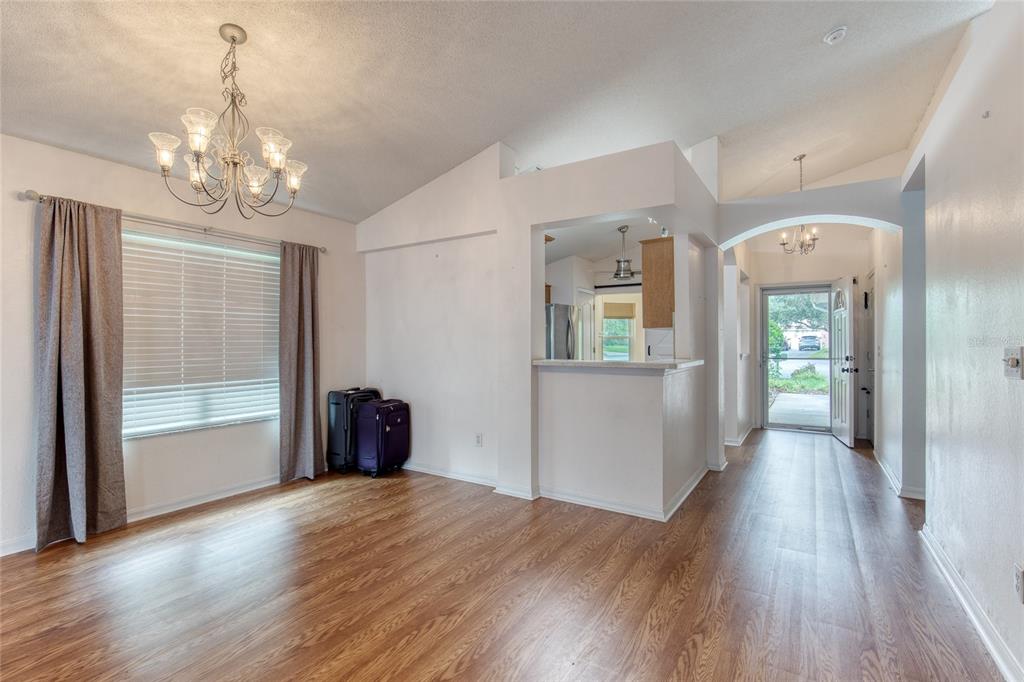 A dining area with wood-look flooring, a chandelier, and an open view into the kitchen — 38 OLD MACON DRIVE, ORMOND BEACH, FL