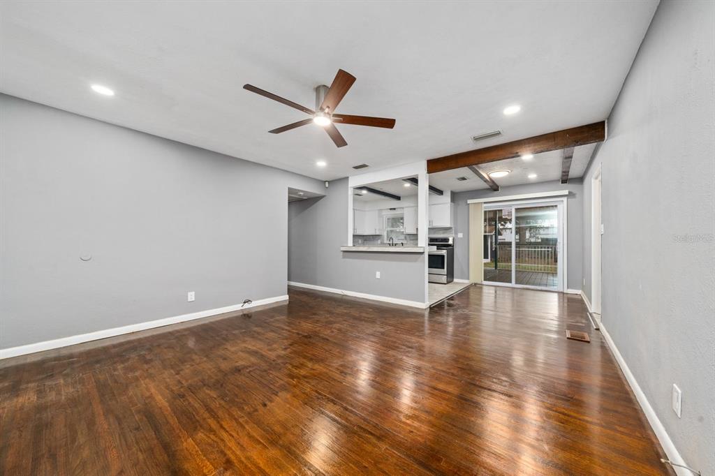 A living room with hardwood floors, a ceiling fan, and an opening to the kitchen — 6531 HILL TOP ROAD, ORLANDO, FL