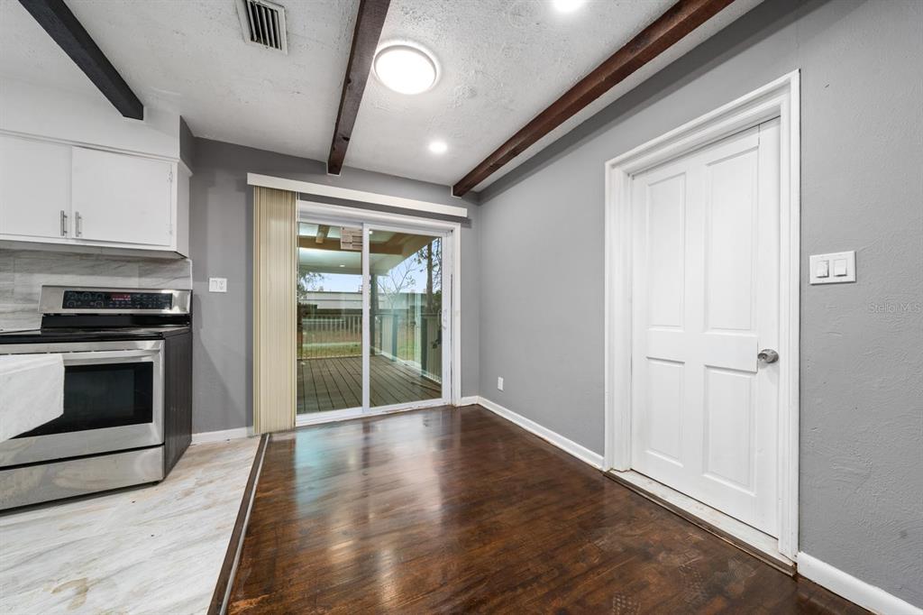 A kitchen and dining area features dark wood floors, exposed ceiling beams, and sliding glass doors — 6531 HILL TOP ROAD, ORLANDO, FL