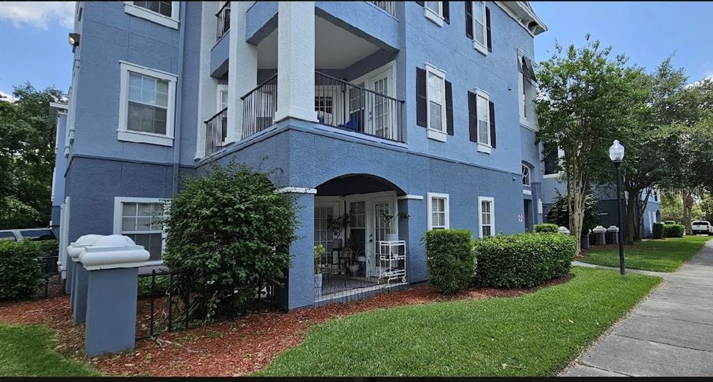 A blue multi-story apartment building with a ground-level patio and a second-floor balcony — 3561 CONROY ROAD UNIT 221, ORLANDO, FL