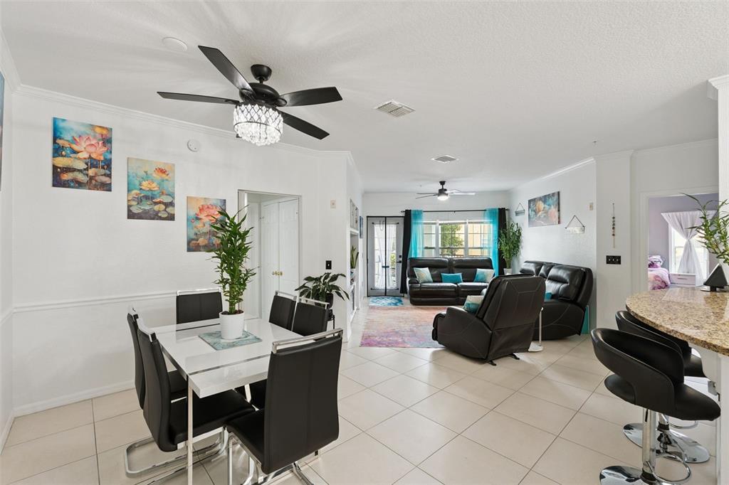 An open-concept living and dining area features tile flooring, a crystal ceiling fan, and furniture — 3561 CONROY ROAD UNIT 221, ORLANDO, FL