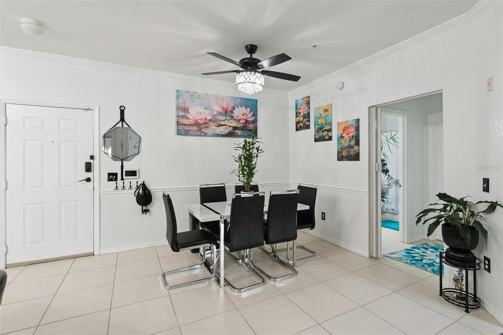 A dining room features a white table, black chairs, a ceiling fan, and floral wall art — 3561 CONROY ROAD UNIT 221, ORLANDO, FL