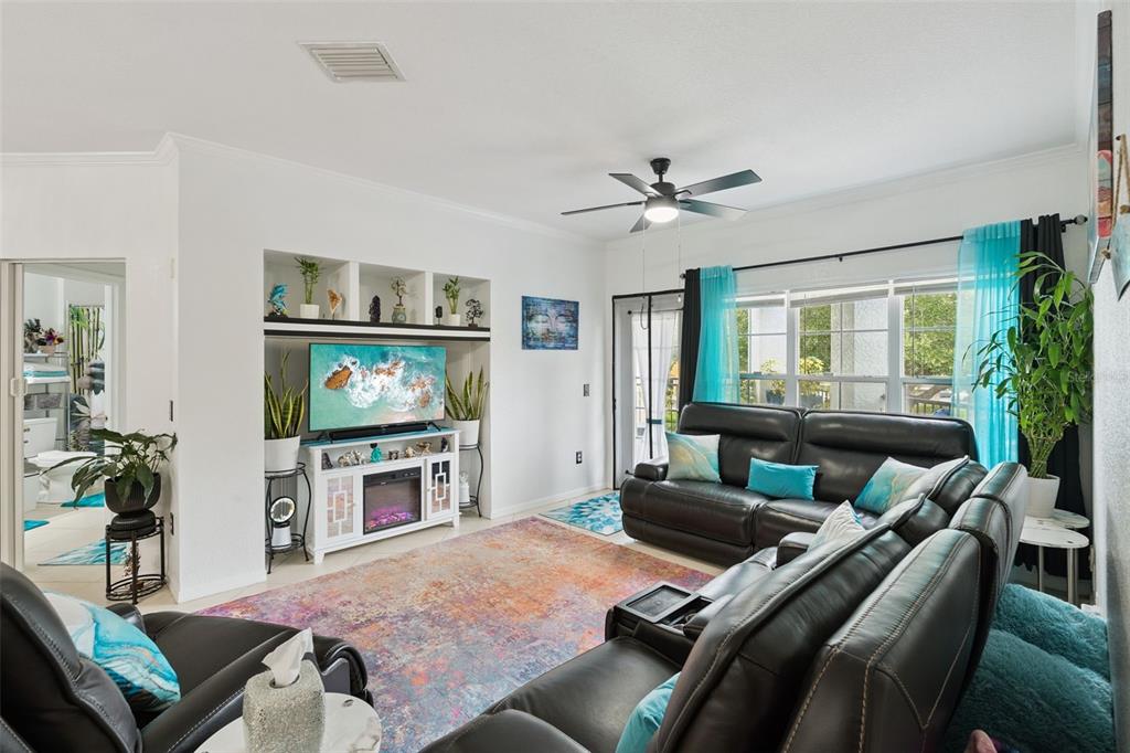 A living room features a dark leather sectional, a fireplace media console, and a large rug — 3561 CONROY ROAD UNIT 221, ORLANDO, FL