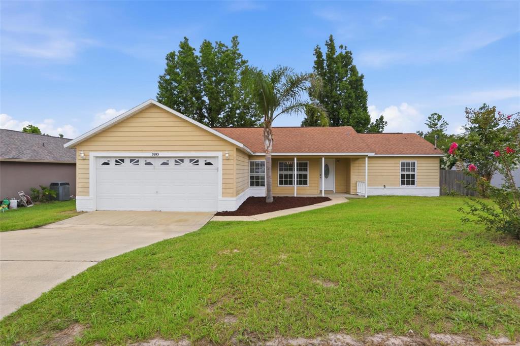 A single-story house with yellow siding, a two-car garage, and a front porch — 2695 KEENE LANE, DELTONA, FL
