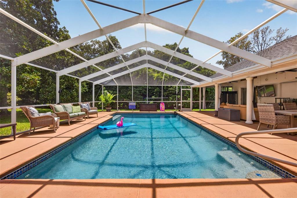 A rectangular swimming pool with a pink flamingo float inside a screened-in lanai enclosure — 4334 DOTTIE COURT, SPRING HILL, FL
