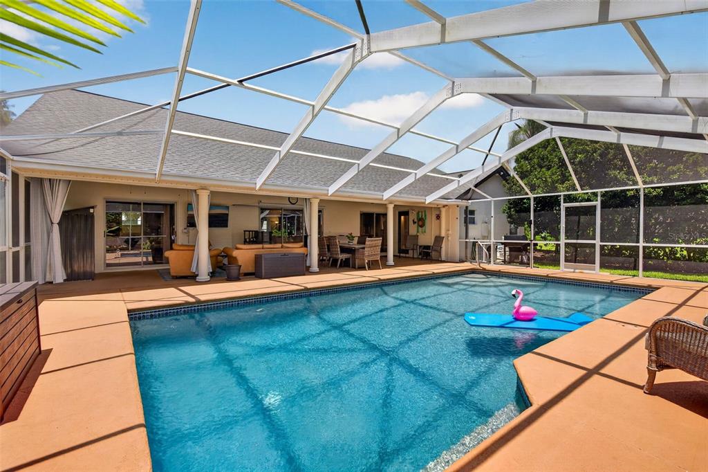 A screened-in swimming pool patio with orange decking and outdoor furniture under a white frame — 4334 DOTTIE COURT, SPRING HILL, FL
