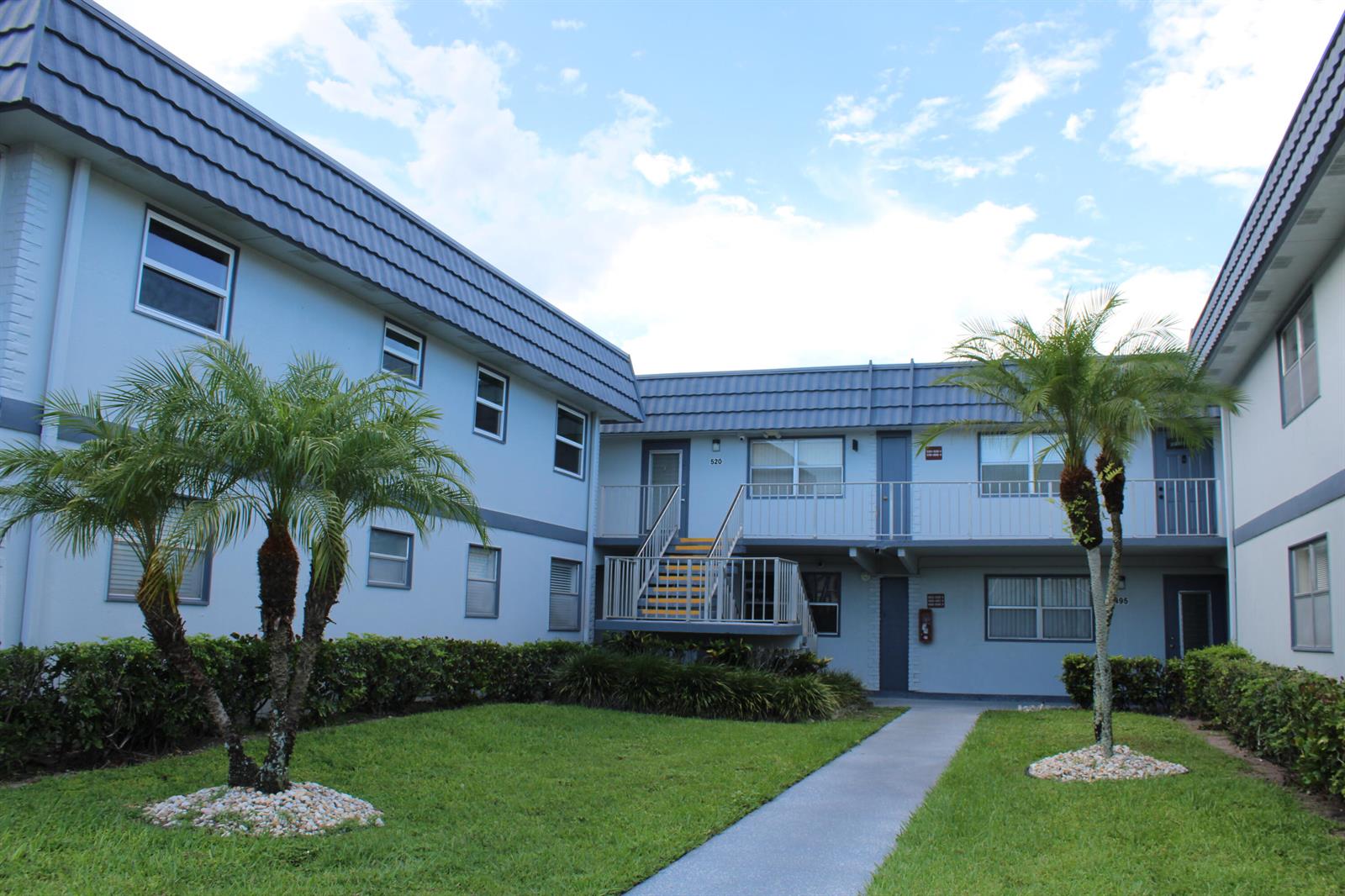 A two-story apartment building with light blue siding, a dark roof, and a central walkway — 520 Brittany K, Delray Beach FL 33446, DELRAY BEACH, FL