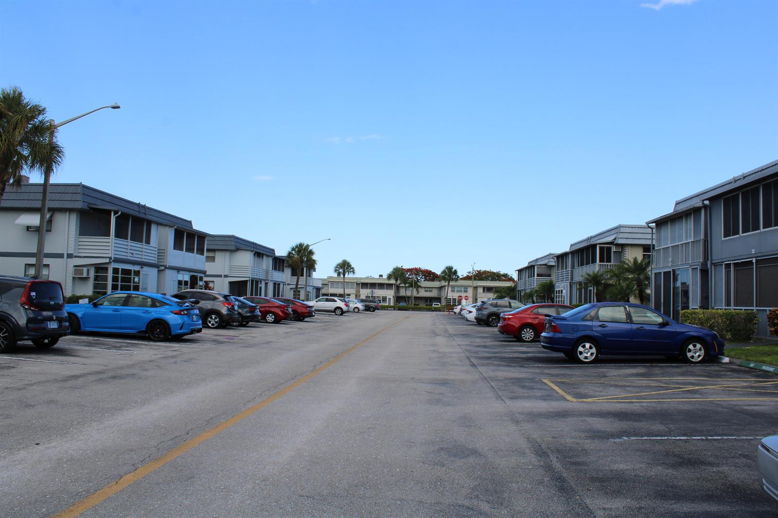 An outdoor parking lot is situated between two rows of multi-story apartment buildings — 520 Brittany K, Delray Beach FL 33446, DELRAY BEACH, FL