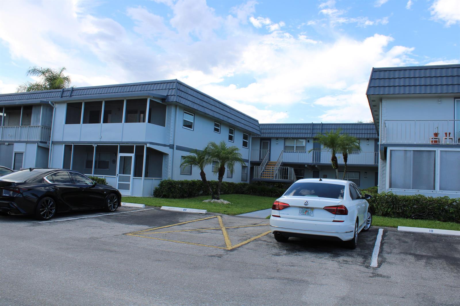 A two-story apartment building with a parking lot and two cars in the foreground — 520 Brittany K, Delray Beach FL 33446, DELRAY BEACH, FL