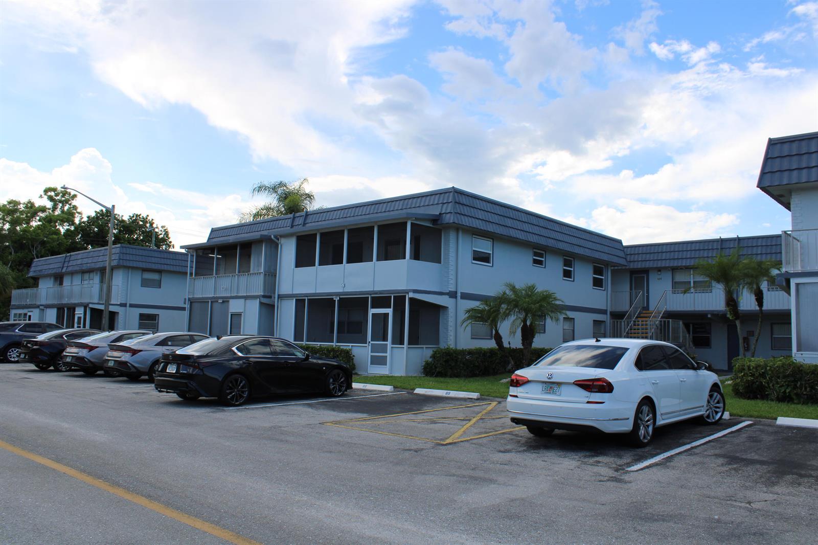 A two-story apartment building with screened balconies and a parking lot in the foreground — 520 Brittany K, Delray Beach FL 33446, DELRAY BEACH, FL