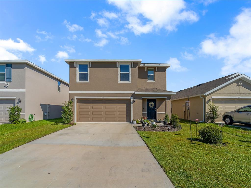 A two-story suburban house with a tan stucco exterior, a two-car garage, and a driveway — 3117 ROCK SOUND STREET, BRADENTON, FL