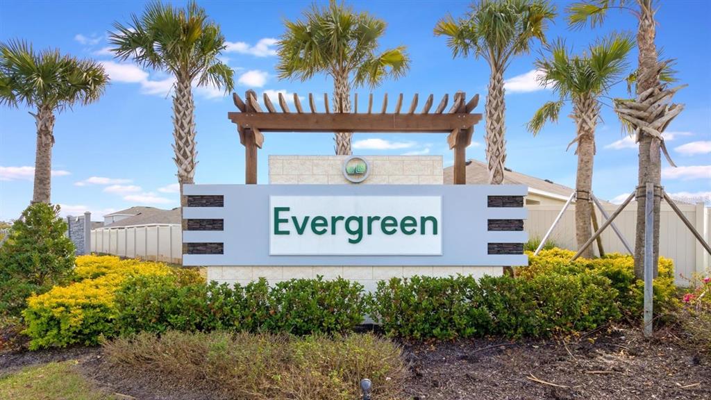 A sign reading Evergreen stands in front of palm trees and a residential fence — 3117 ROCK SOUND STREET, BRADENTON, FL