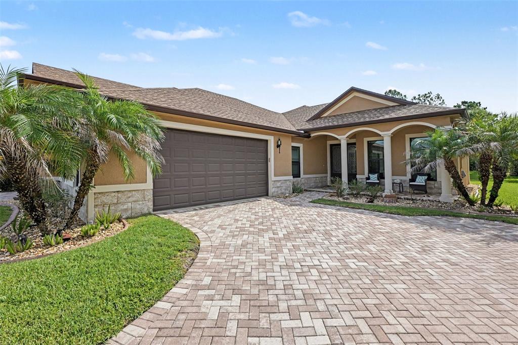 A single-story house with a brown garage, stone accents, and a paved driveway — 429 HARMONY LANE, TITUSVILLE, FL