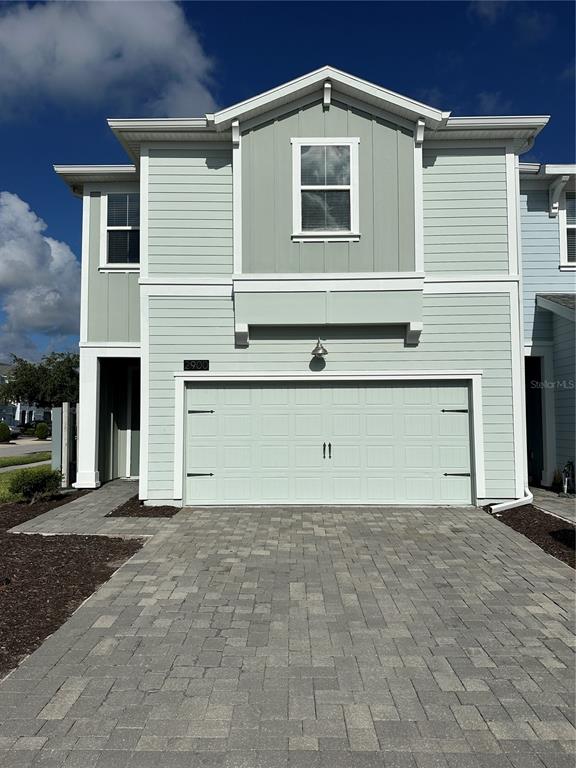 A two-story townhouse with light green siding, a two-car garage, and a paver driveway — 2900 TITLE STREET, KISSIMMEE, FL
