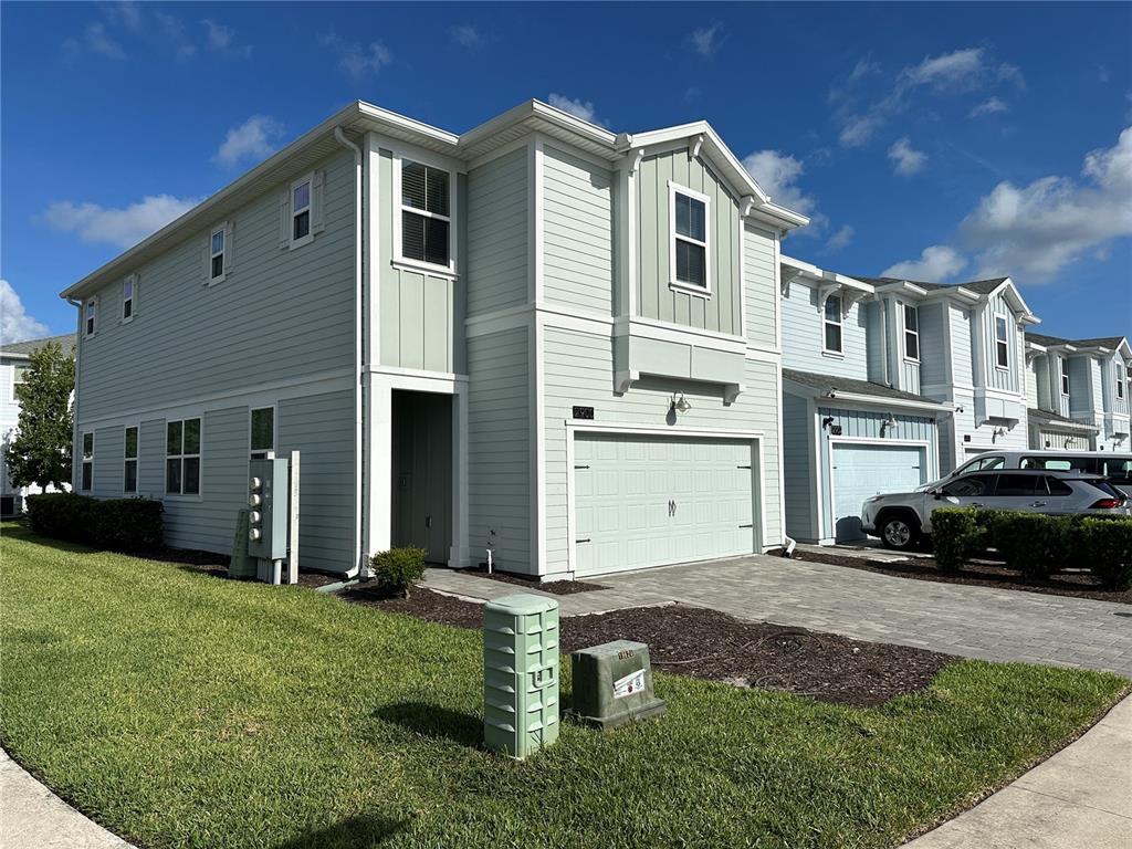 A two-story light green townhouse with a single-car garage and a paved driveway — 2900 TITLE STREET, KISSIMMEE, FL