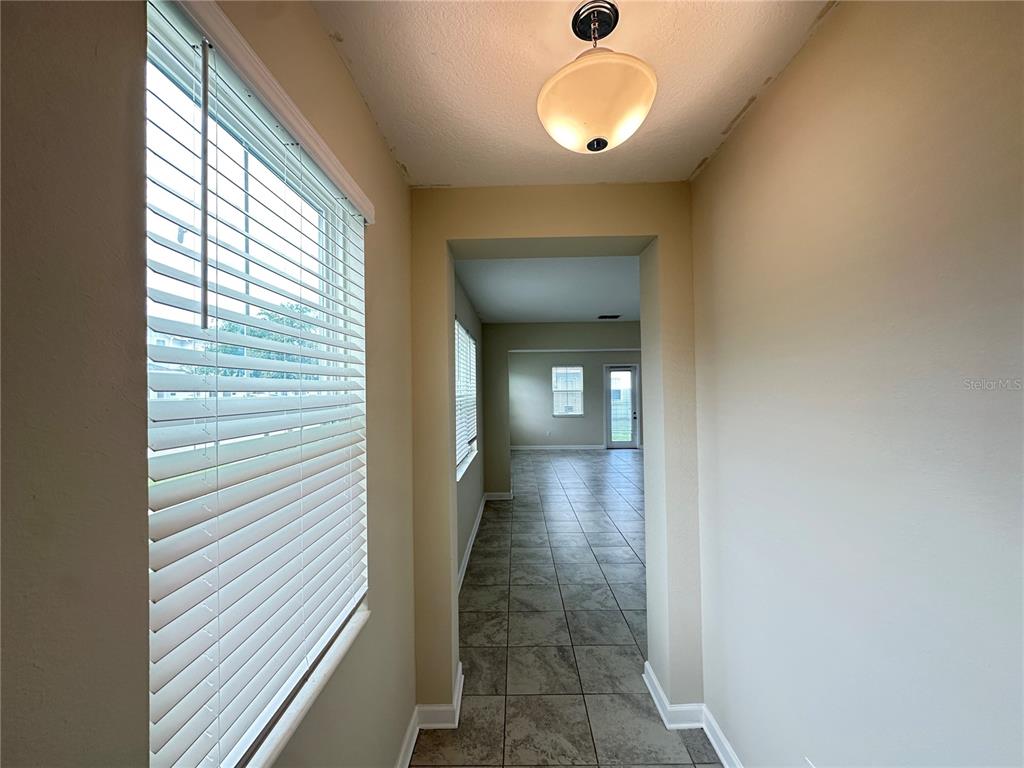 A hallway with tile flooring leads to an open living area with a glass door — 2900 TITLE STREET, KISSIMMEE, FL