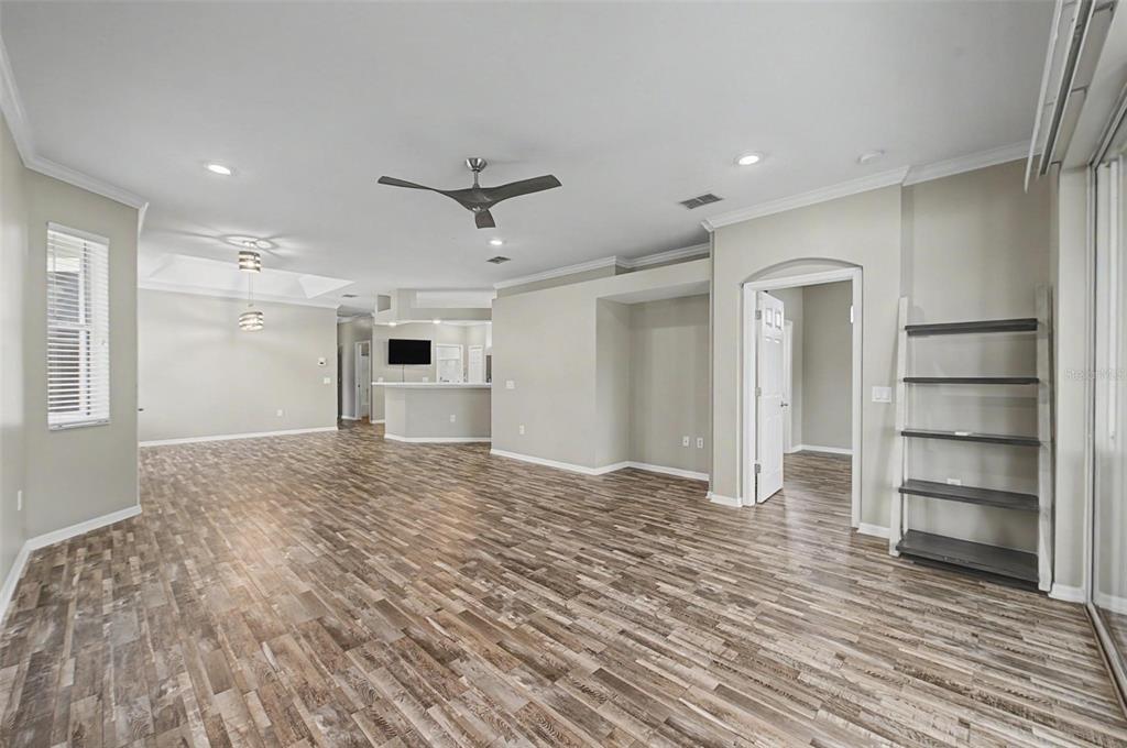 An open-concept living area features wood-look flooring, a ceiling fan, and a built-in shelving unit — 8046 PONKAN ROAD, LAND O LAKES, FL
