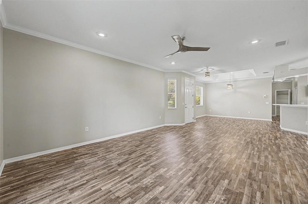An empty living room features light gray walls, wood-look flooring, recessed lighting, and a ceiling fan — 8046 PONKAN ROAD, LAND O LAKES, FL