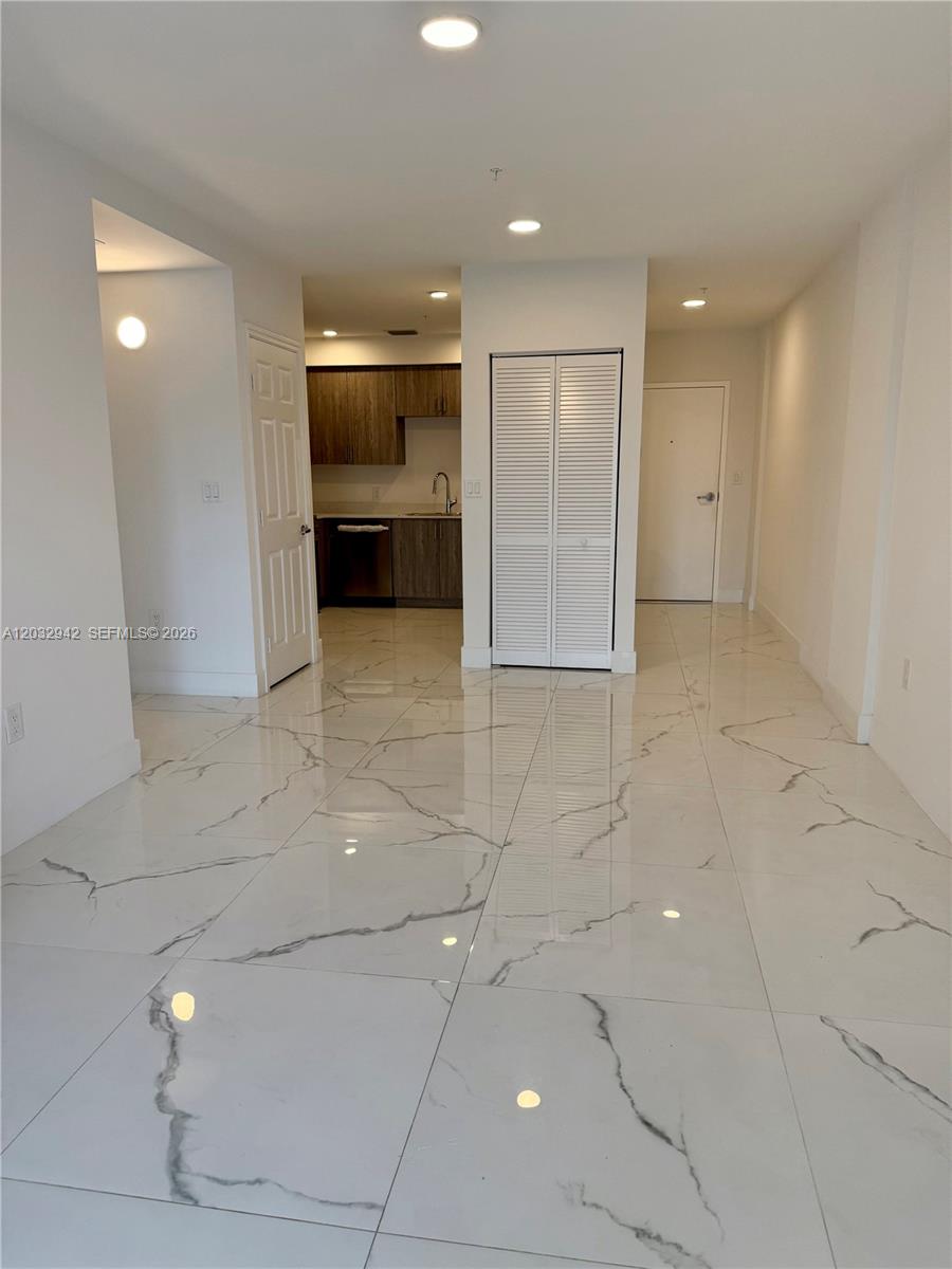 A bright room features white marble-patterned tile flooring, a small kitchen, and white louvered doors — 11150 NW 82nd St # 409, Doral FL 33178, DORAL, FL