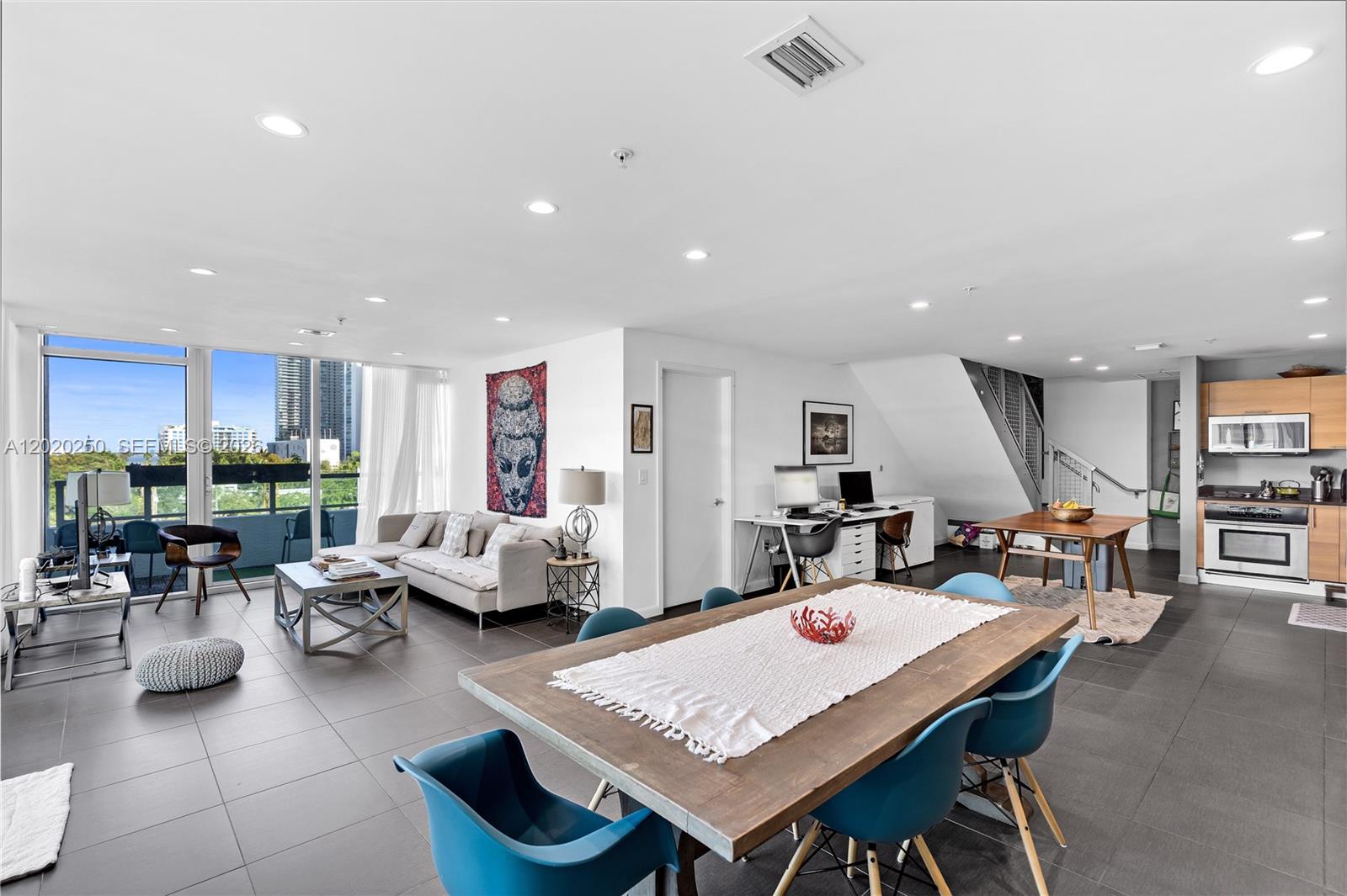 An open-concept living and dining area features tile flooring, a modern kitchen, and balcony access — 3301 NE 1st Ave # M0513, Miami FL 33137, MIAMI, FL