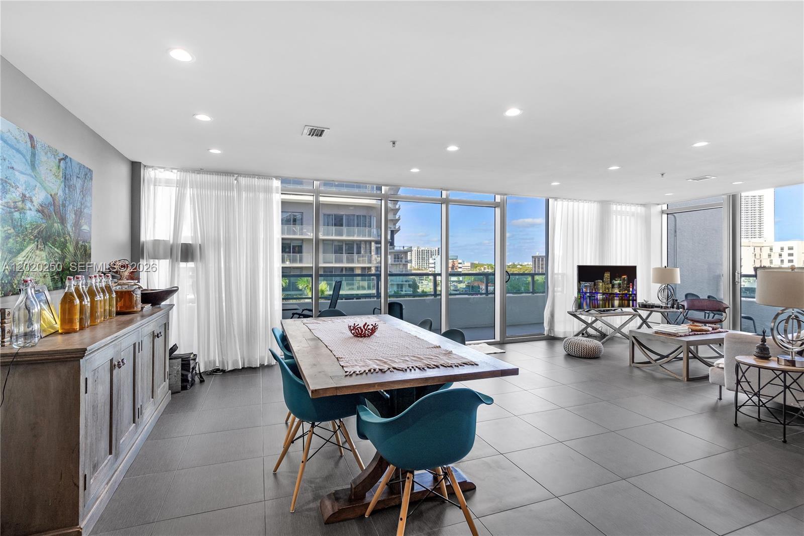 A modern dining and living area features tile floors, floor-to-ceiling windows, and a balcony view — 3301 NE 1st Ave # M0513, Miami FL 33137, MIAMI, FL