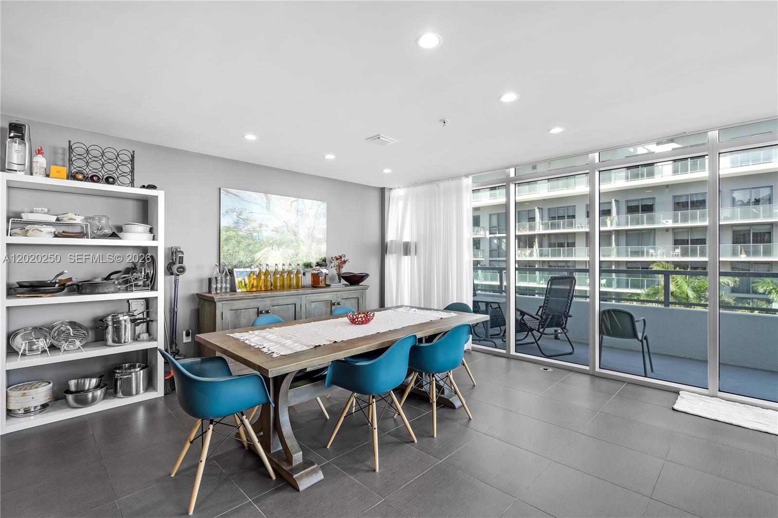 A dining room features a wooden table, blue chairs, open shelving, and floor-to-ceiling windows — 3301 NE 1st Ave # M0513, Miami FL 33137, MIAMI, FL