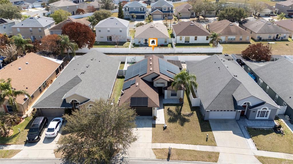 An aerial view shows a suburban house with solar panels on its roof — 2822 MOULTRIE CREEK DRIVE, KISSIMMEE, FL
