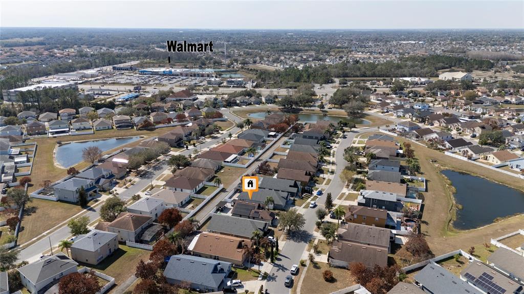 An aerial view shows a suburban neighborhood with houses, ponds, and a distant Walmart store — 2822 MOULTRIE CREEK DRIVE, KISSIMMEE, FL