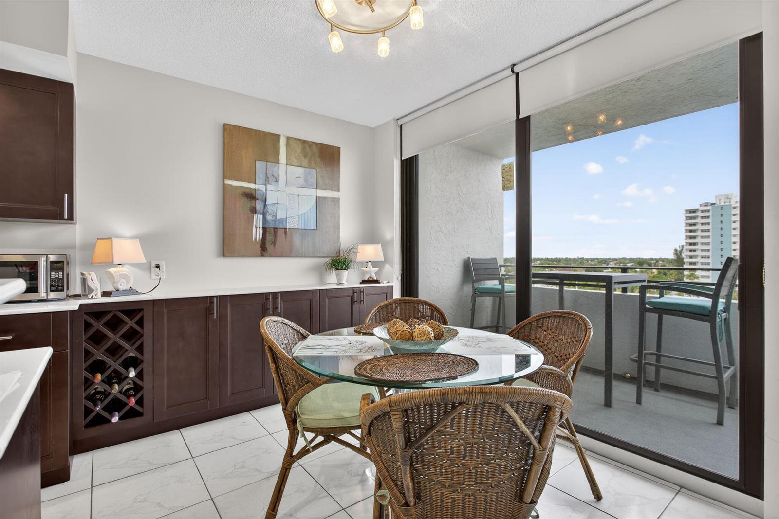 A dining area with a glass table, wicker chairs, dark cabinetry, and a balcony view — 1500 N Ocean Boulevard # 602, Pompano Beach FL 33062, POMPANO BEACH, FL