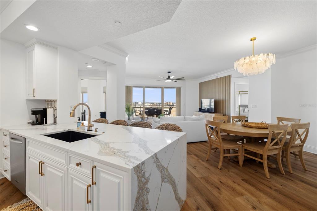 A kitchen island with a marble countertop overlooks a dining area and a living room — 11 BAYMONT STREET UNIT 909, CLEARWATER BEACH, FL