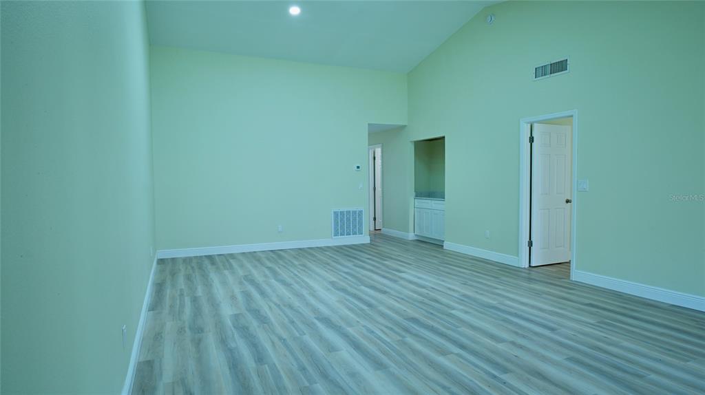 A room with light green walls, wood-look flooring, a sliding glass door, and white closets — 2317 SUN VALLEY CIRCLE UNIT 2317, WINTER PARK, FL
