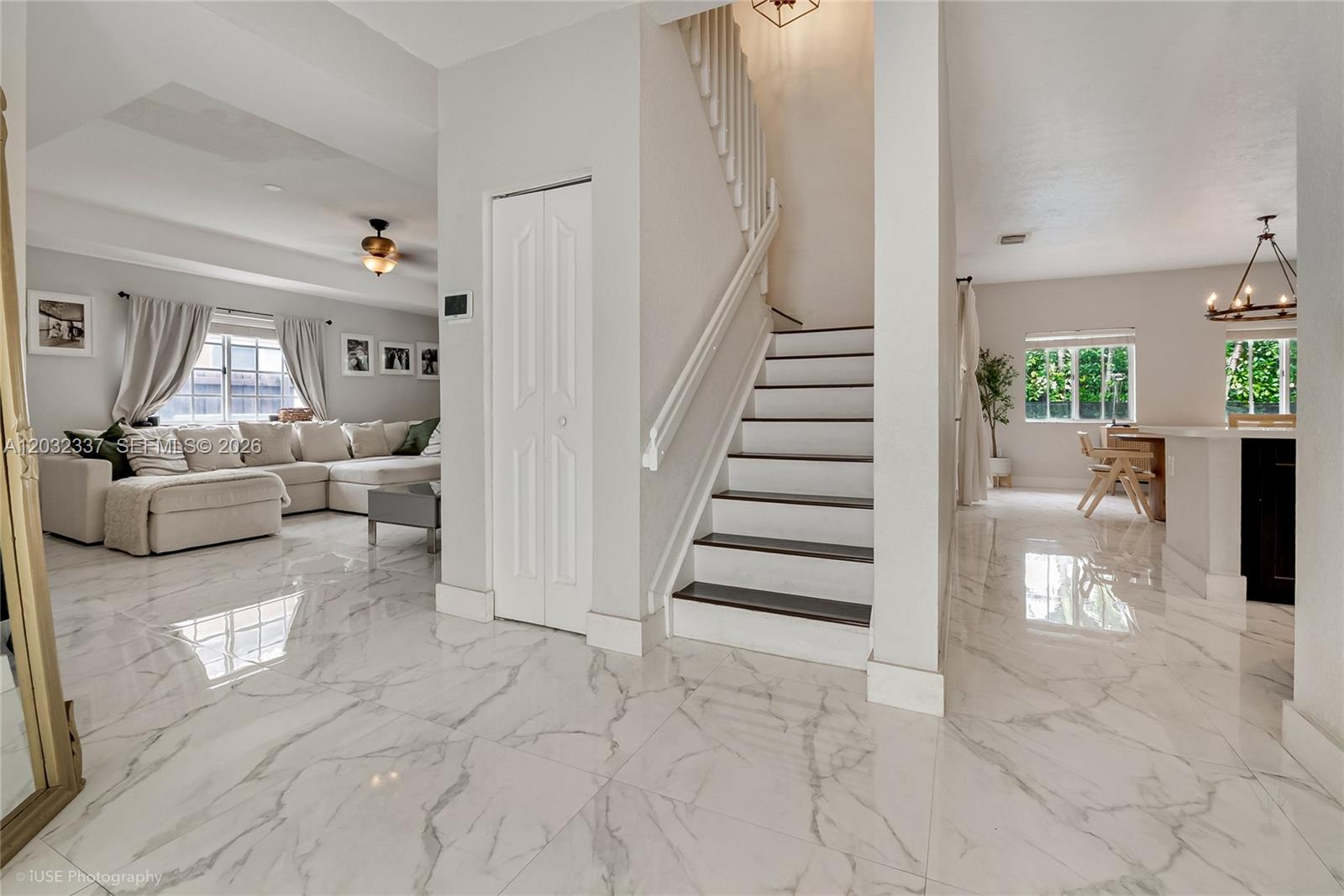 A bright entryway features a staircase, white marble-look tile flooring, and views into the living area — 4147 NE 30th St, Homestead FL 33033, HOMESTEAD, FL
