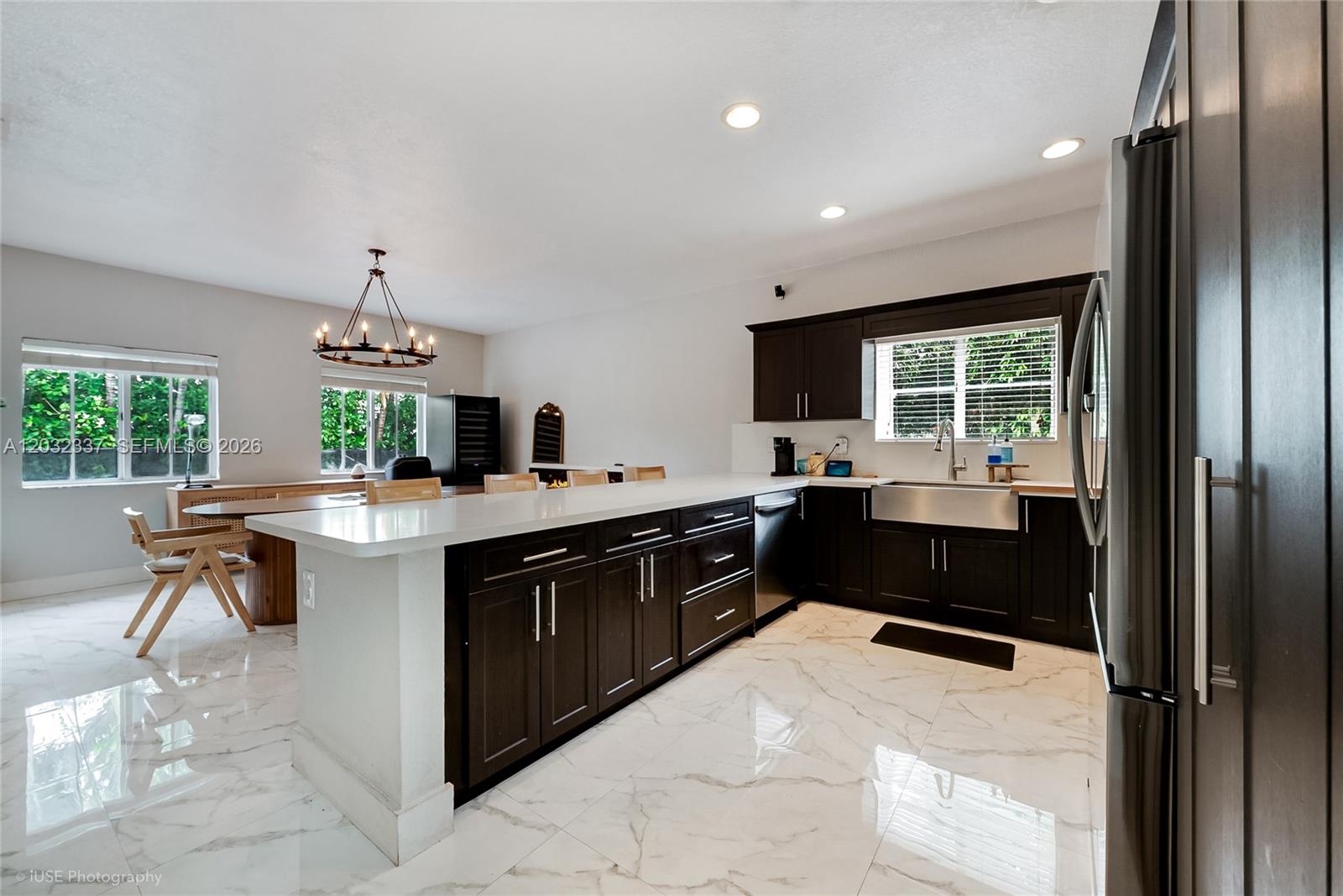 A modern kitchen features dark wood cabinetry, white countertops, and marble-patterned tile flooring — 4147 NE 30th St, Homestead FL 33033, HOMESTEAD, FL