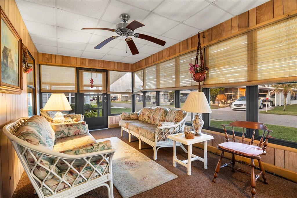 A sunroom features wood-paneled walls, wicker furniture, a ceiling fan, and large windows — 6775 BRENTWOOD DRIVE NE, WINTER HAVEN, FL