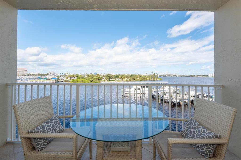 A balcony with a glass-topped table and two chairs overlooks a marina and bridge — 533 MARINA POINT DRIVE UNIT 533, DAYTONA BEACH, FL