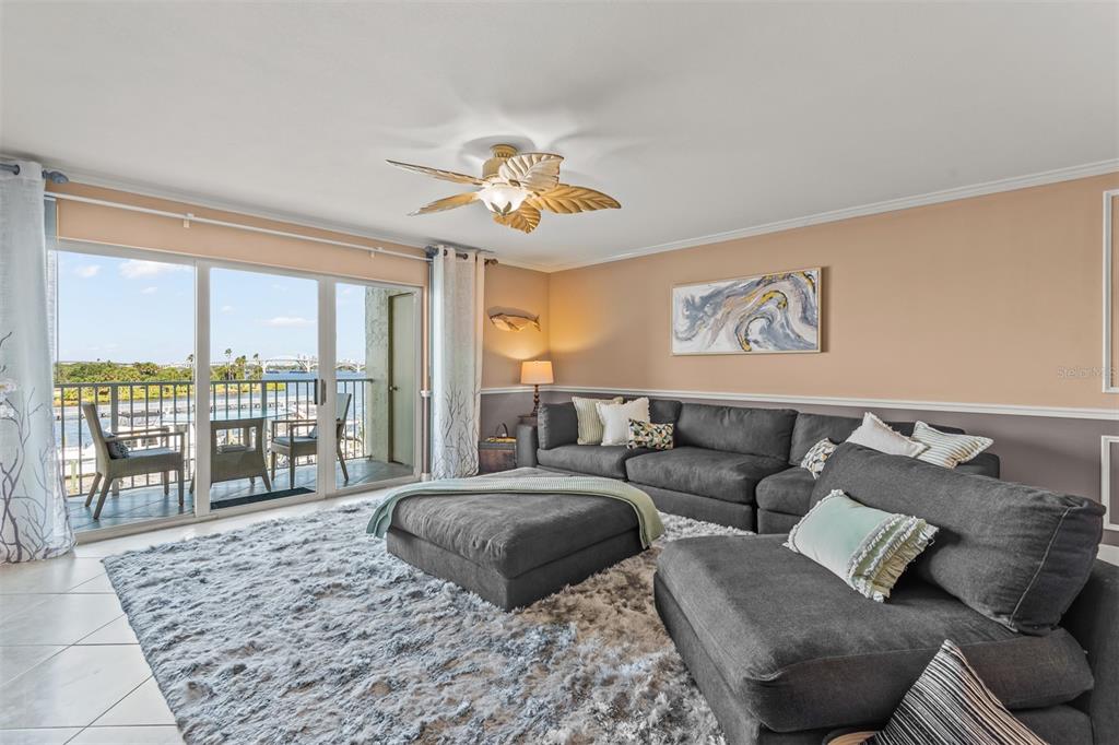 A living room features a large gray sectional, a shaggy rug, and a balcony view — 533 MARINA POINT DRIVE UNIT 533, DAYTONA BEACH, FL