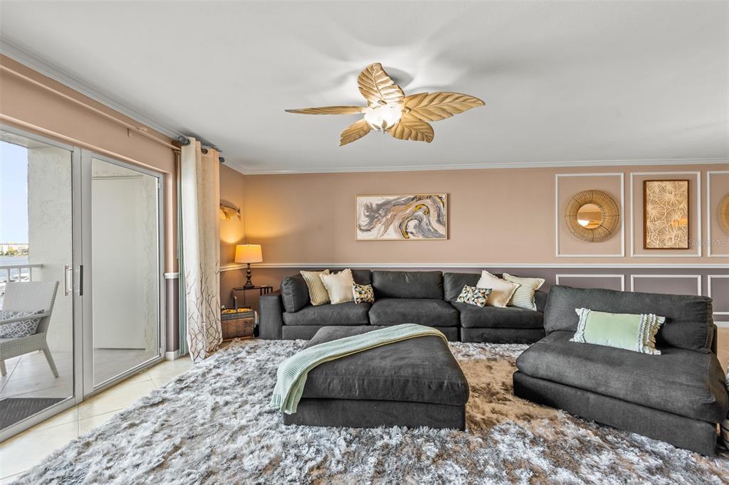 A living room features a dark sectional sofa, a large shag rug, and a ceiling fan — 533 MARINA POINT DRIVE UNIT 533, DAYTONA BEACH, FL