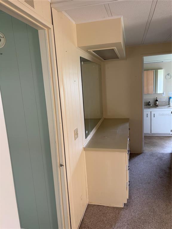 A hallway vanity area with a mirror, countertop, and drawers leads to a bathroom — 3417 N CITRUS CIRCLE UNIT 1633, ZELLWOOD, FL