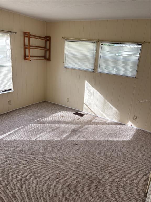 An empty bedroom features beige paneled walls, carpeted flooring, and two windows with blinds — 3417 N CITRUS CIRCLE UNIT 1633, ZELLWOOD, FL