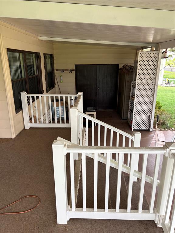 A covered porch features white railings, a set of stairs, and a dark storage shed — 3417 N CITRUS CIRCLE UNIT 1633, ZELLWOOD, FL
